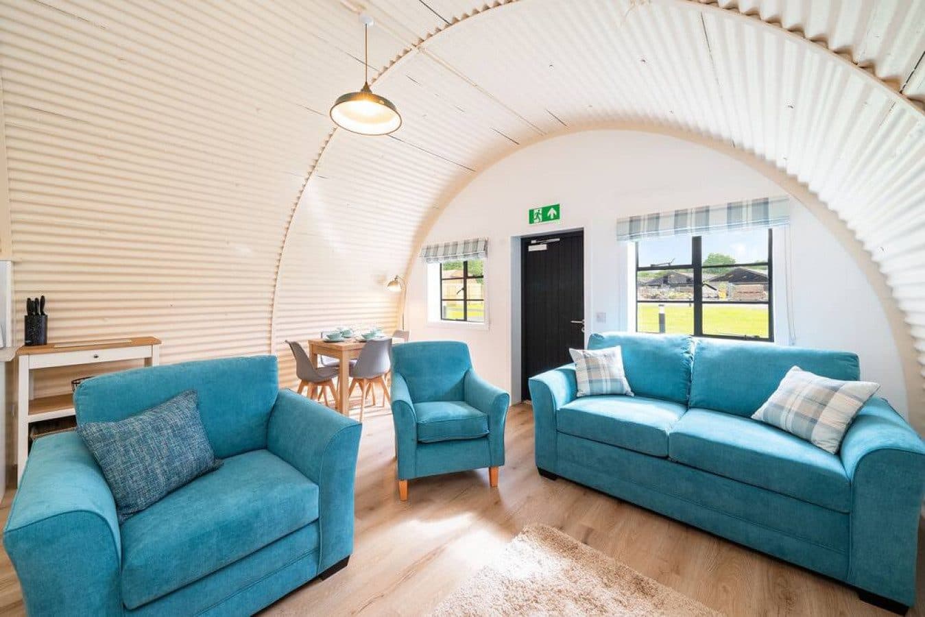 Lounge interior of a converted self-catering Nissen hut at Cultybraggan Camp — warm, timber-framed, and comfortable